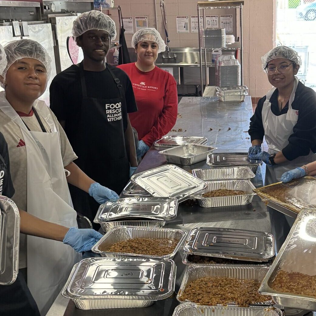 A group of people standing around trays filled with food.