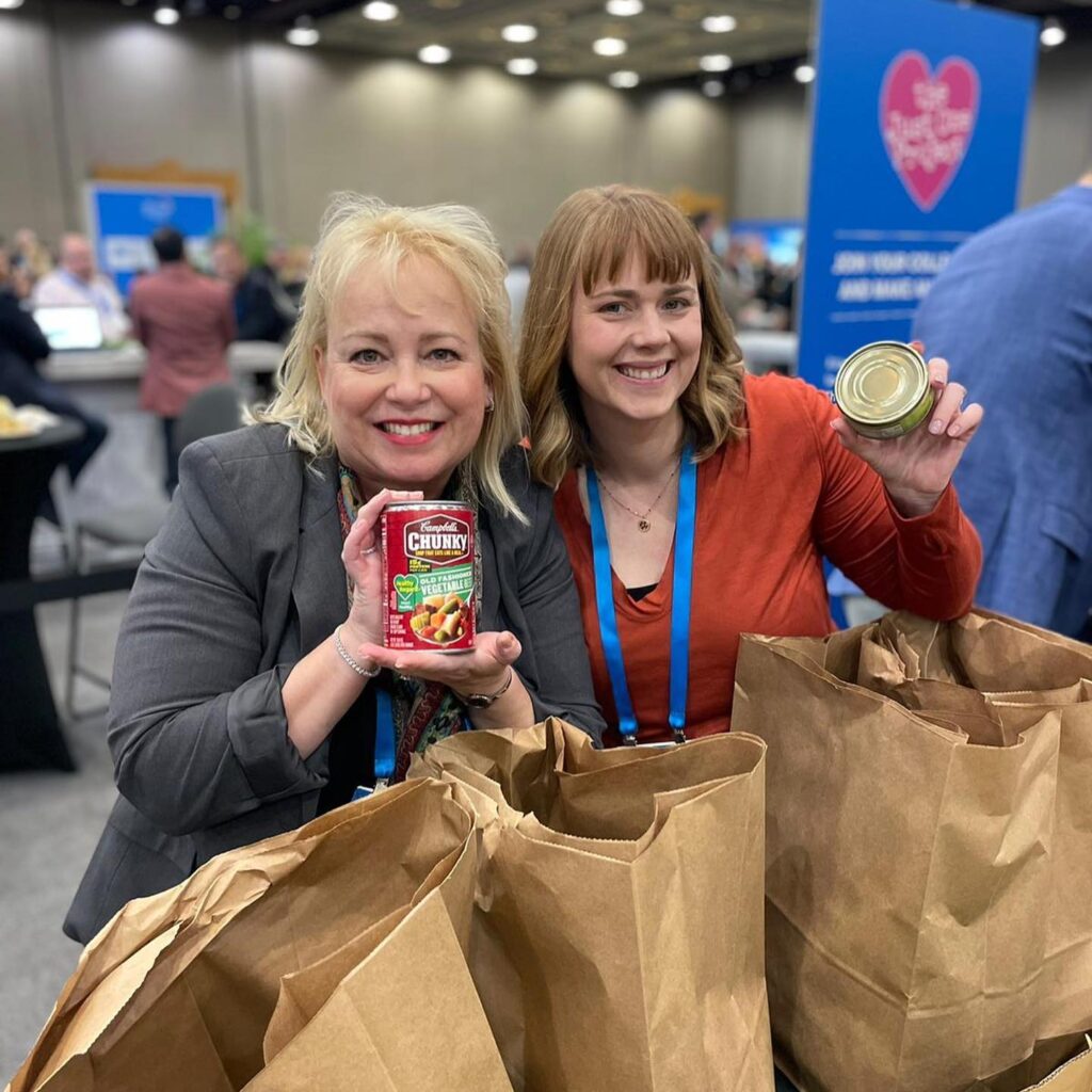 Two women holding bags of food and a jar.