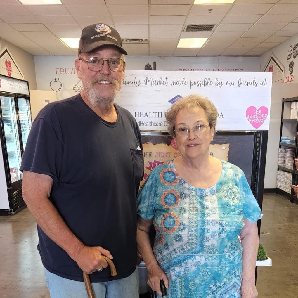 A man and woman standing in front of a sign.