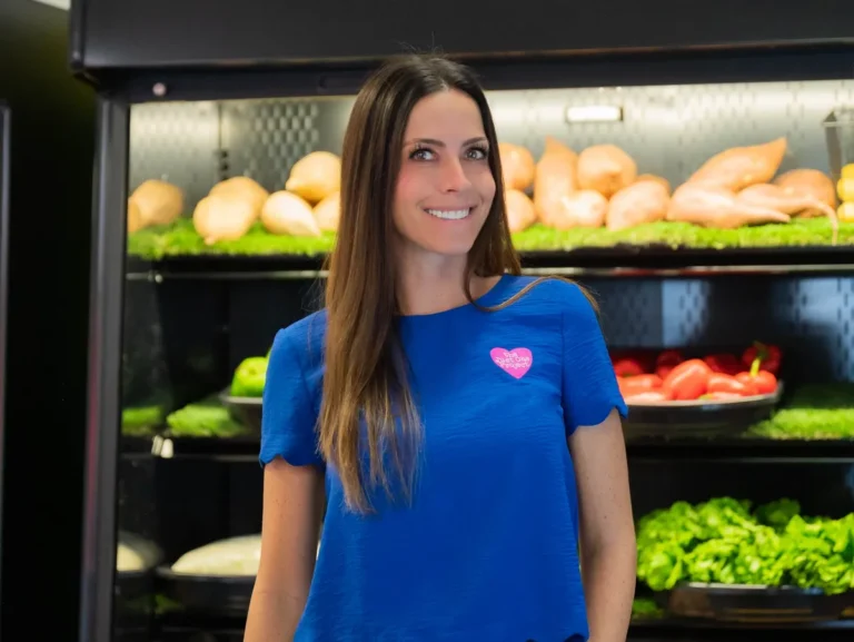 A woman standing in front of shelves filled with produce.