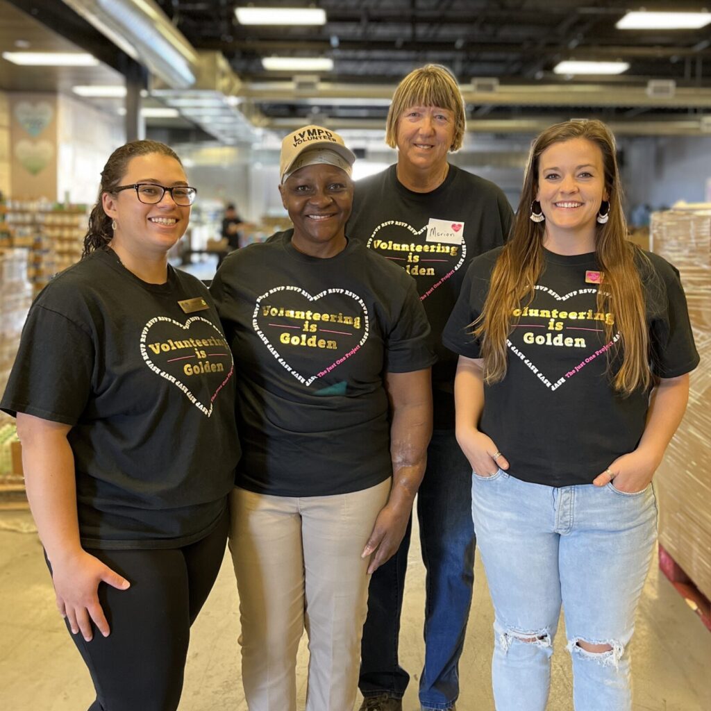 Image of a group of people posing for a photo wearing shirts that say "Volunteering Is Golden"