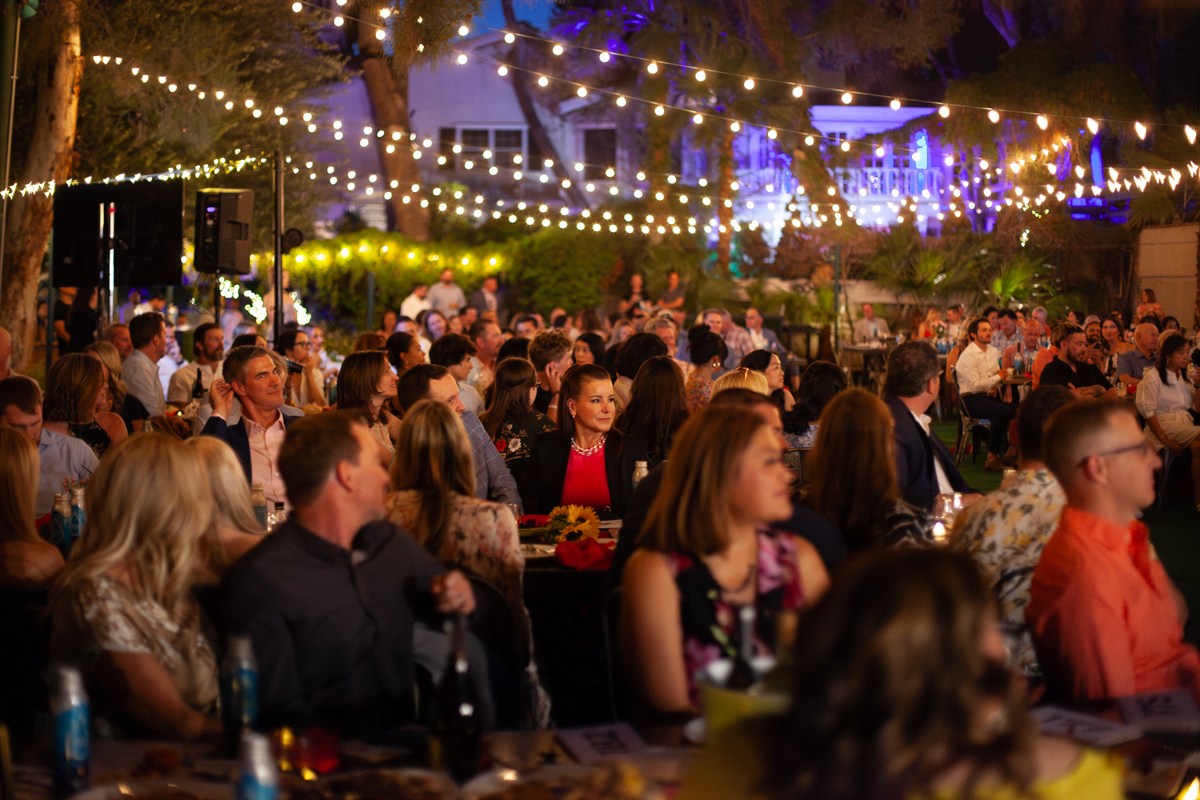 A crowd of people sitting at tables under lights.