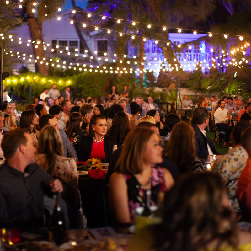 A crowd of people sitting at tables under lights.
