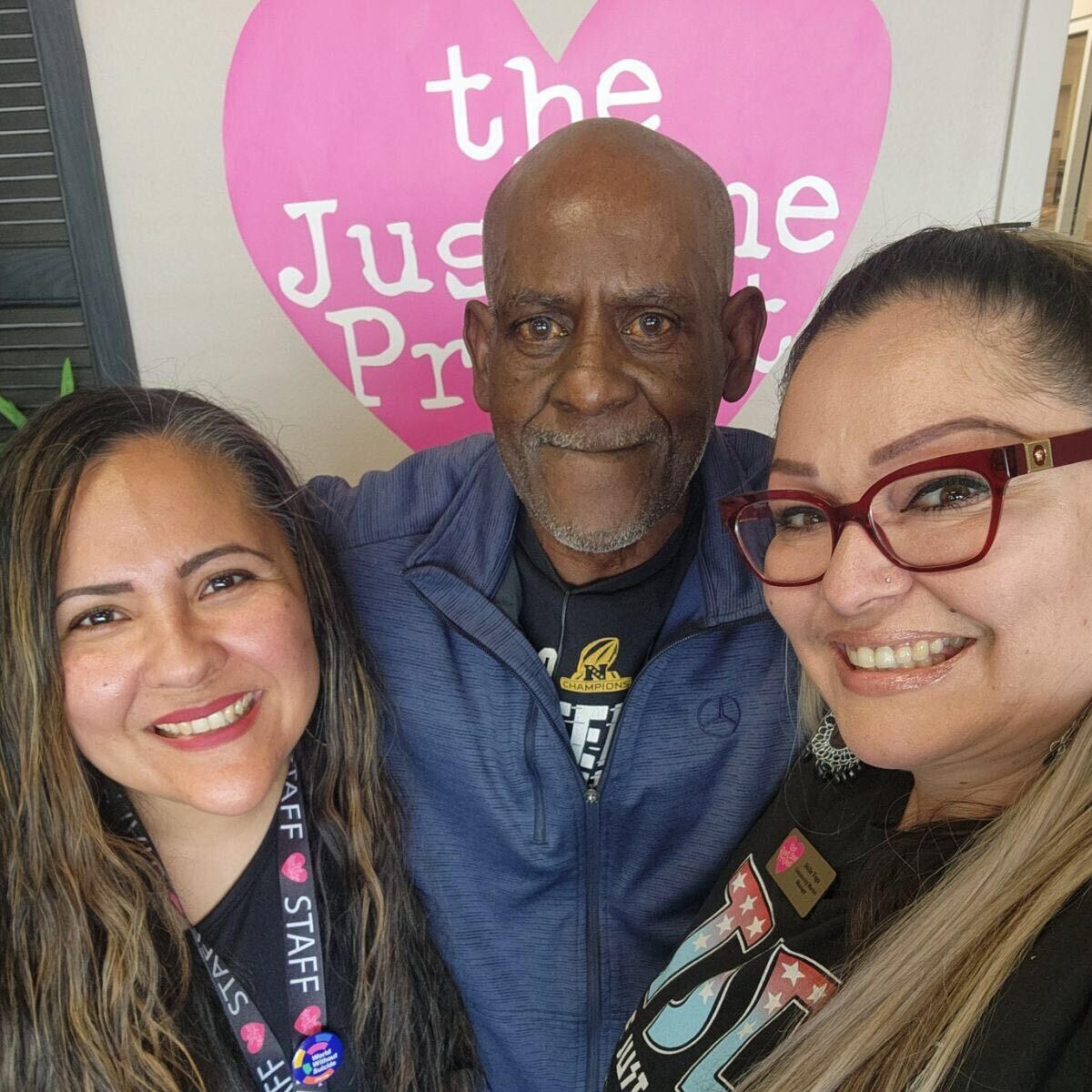 Three people posing for a picture with an older man.