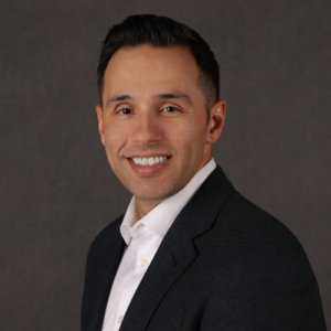 A man in a suit and tie smiling for the camera.
