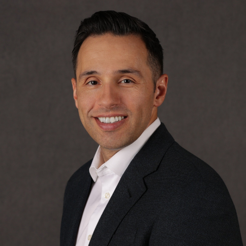 A man in a suit and tie smiling for the camera.