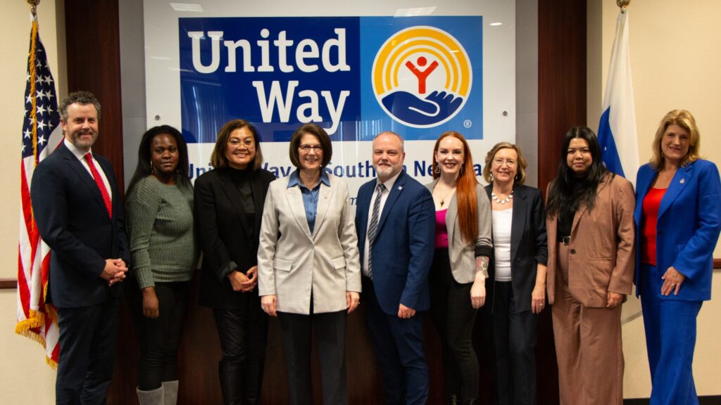 A group of people standing in front of a united way sign.