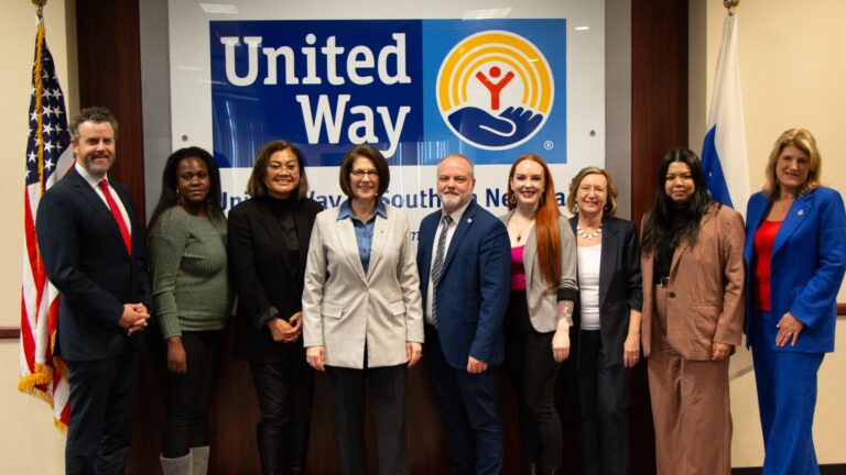A group of people standing in front of a united way sign.