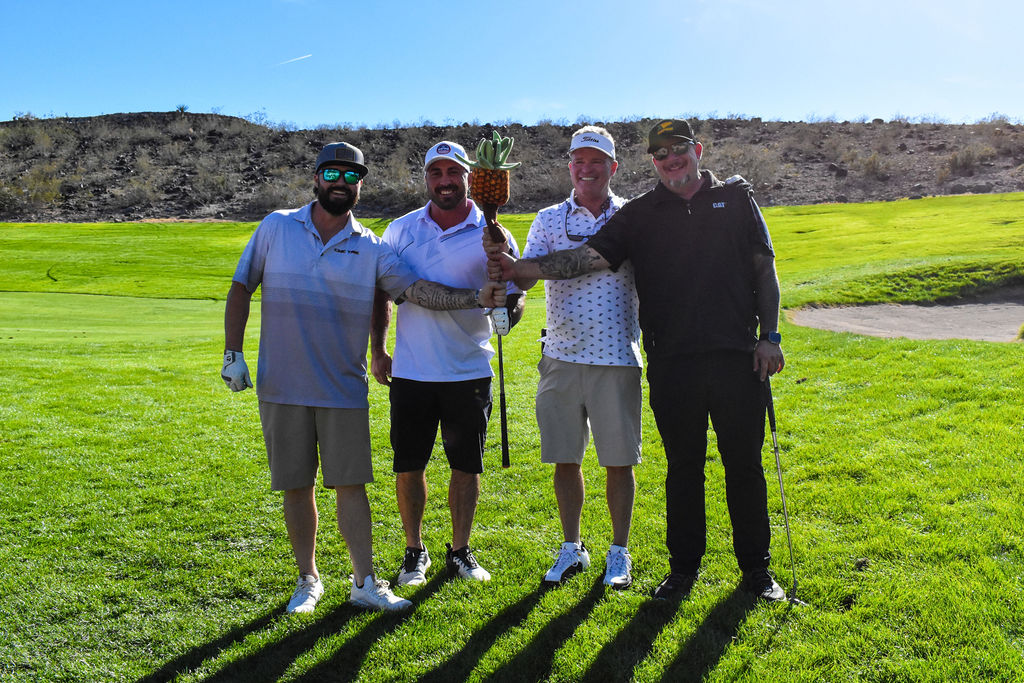 Four men on a golf course smiling into the camera.
