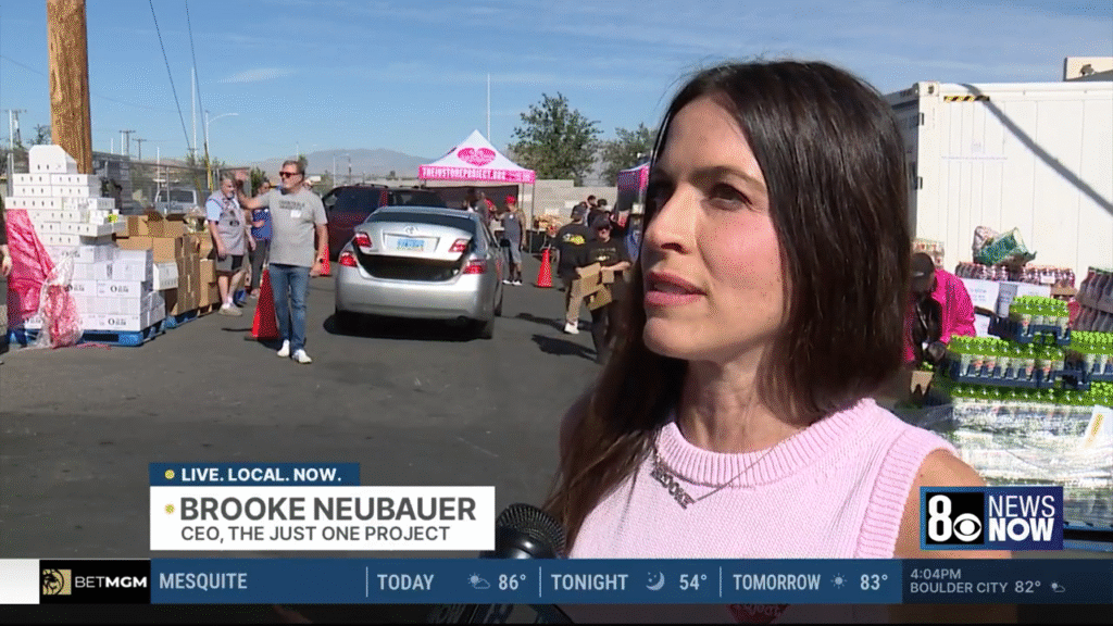 Brooke Neubauer, CEO of The Just One Project, speaks with 8 News Now during emergency food distribution as hundreds of families line up to receive groceries in response to the SNAP benefit pause.