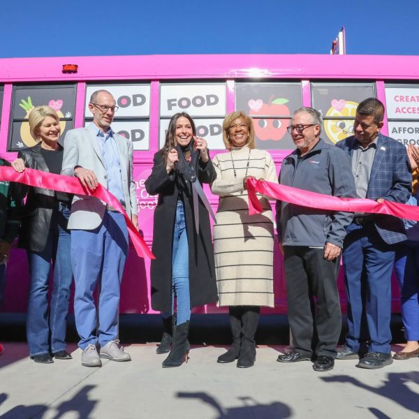 A group of people standing in front of a pink food truck.